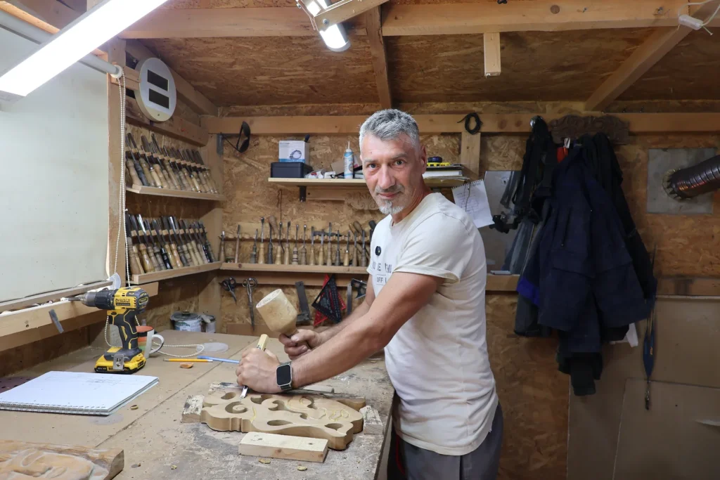 Ionuț cioplind lemnul cu dalta și maiul, în atelierul său de sculptură din Rotunda