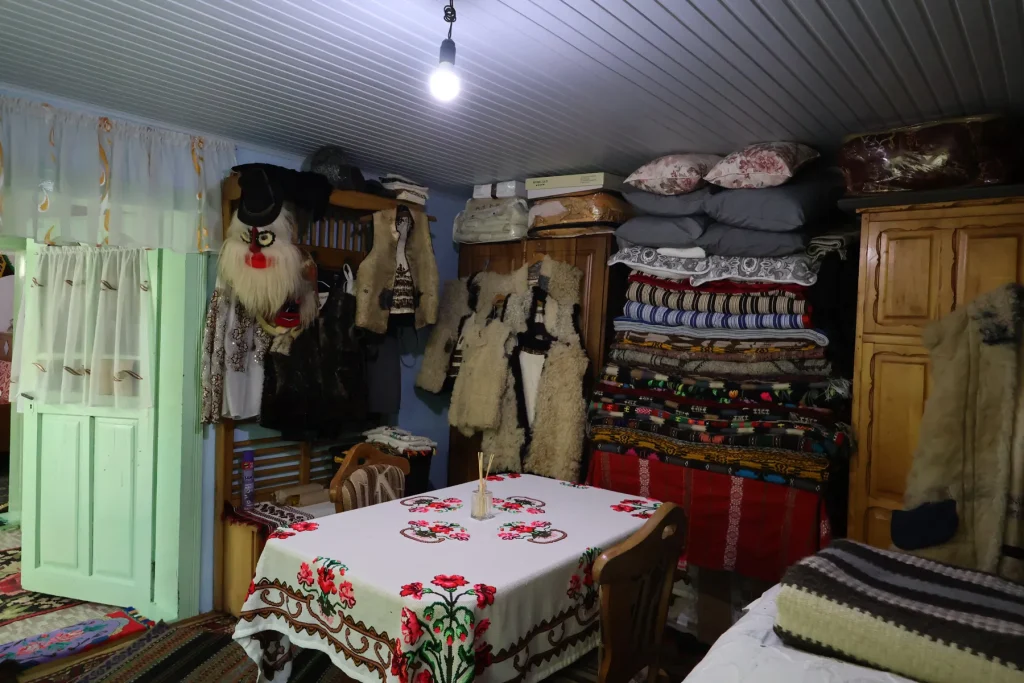 Interior țărănesc la Casa Cojocarului Opincă, cu cojoace, mască tradițională și țesături