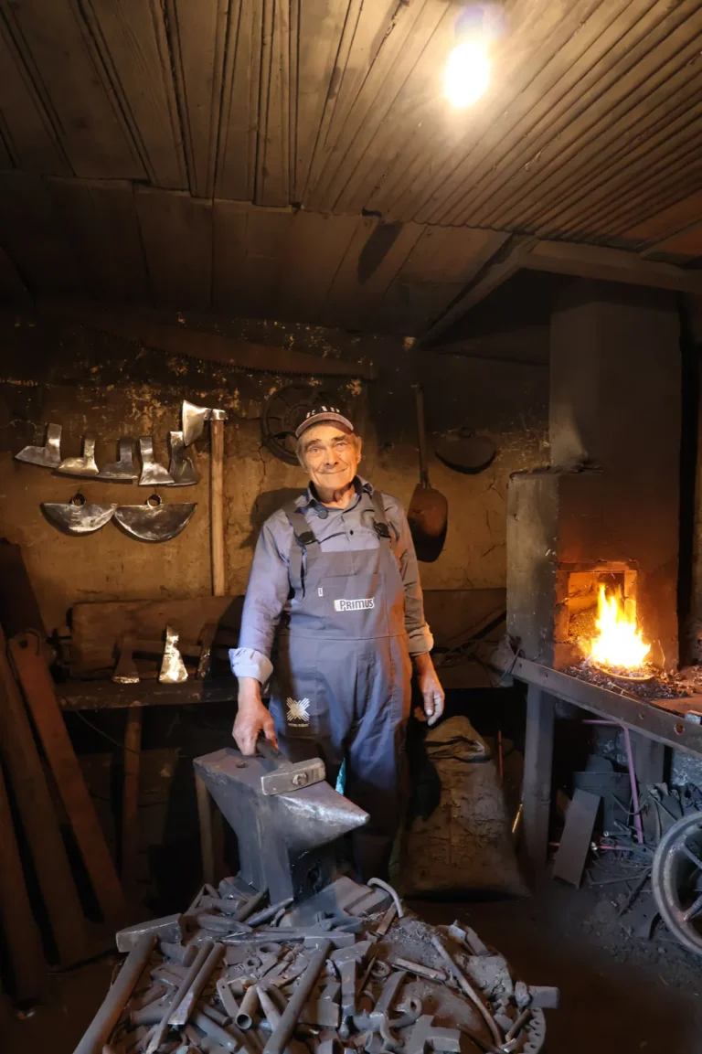 Fierarul lucrând la nicovală lângă focul din forjă, la Fierăria Arotărițe din Rotunda