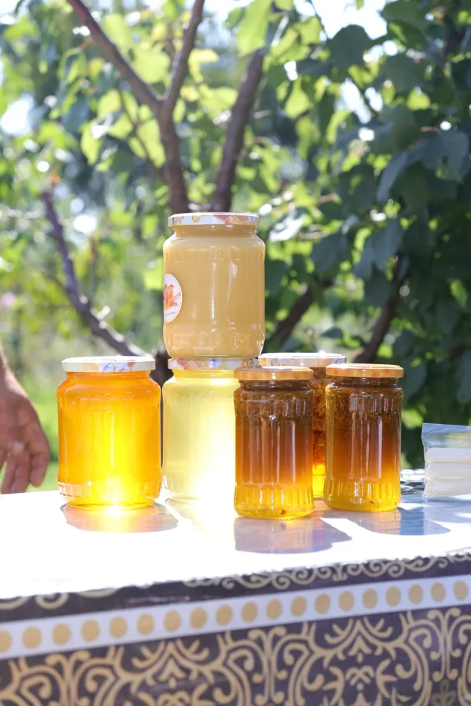 Borcane cu miere de la Prisaca Rotunzii, expuse pe o masă în livadă
