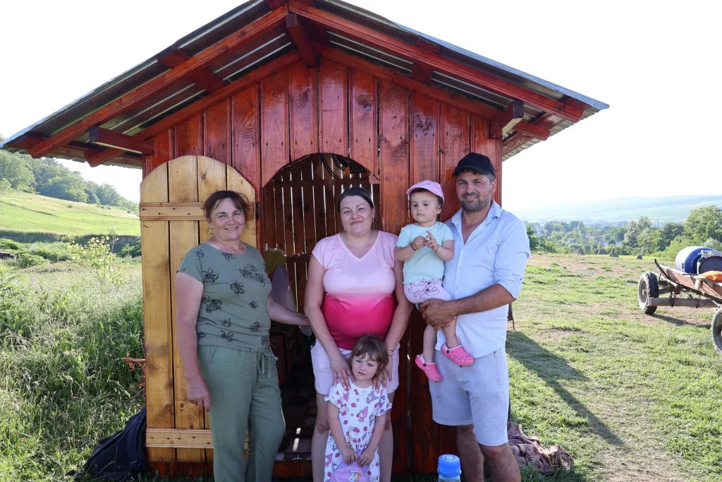 Familia Damian în fața stânei de lemn, pe dealul de la marginea satului Rotunda